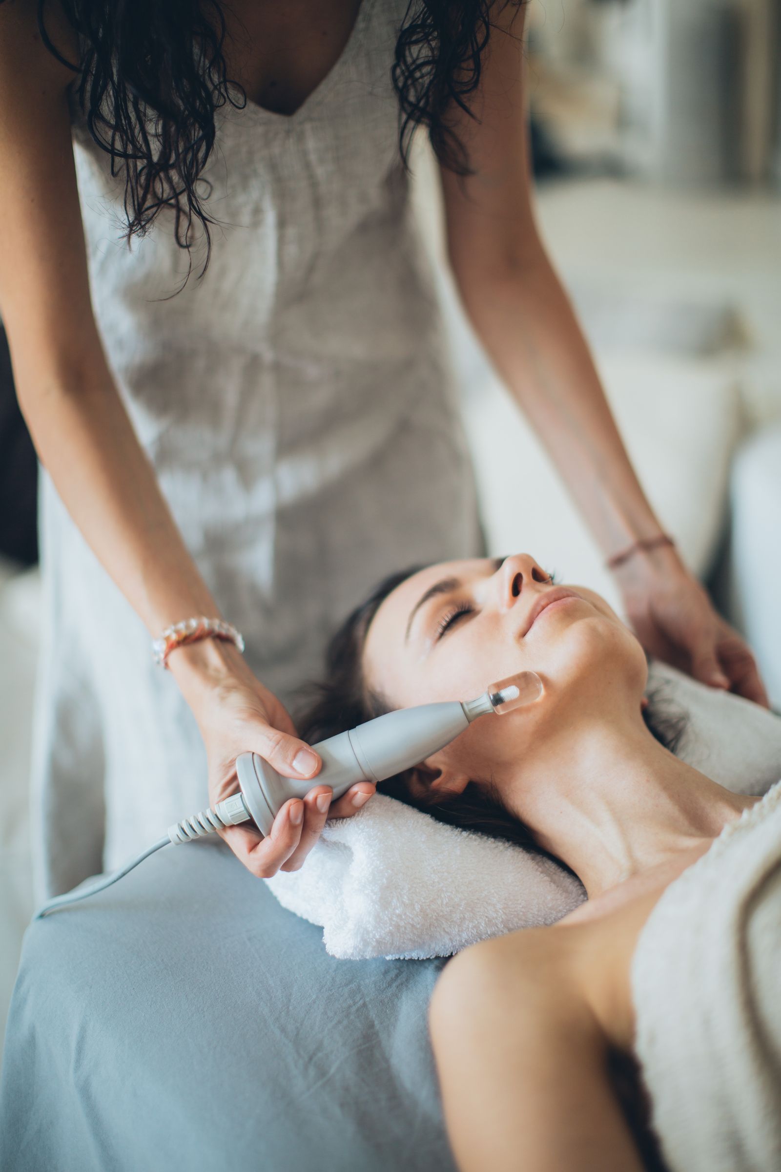 Woman lying down receiving a laser skincare device treatment