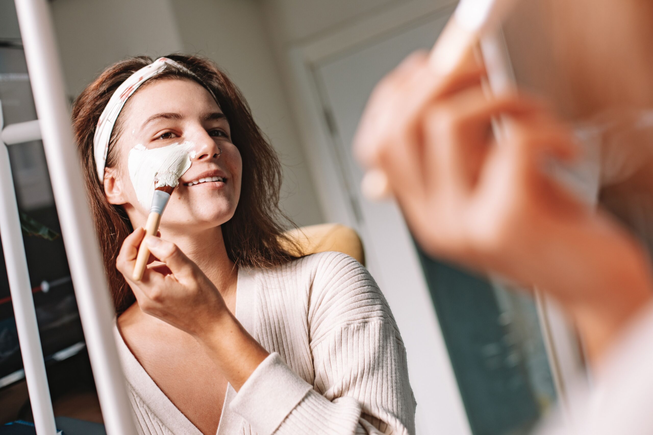 Woman applying a skincare product while looking in the mirror